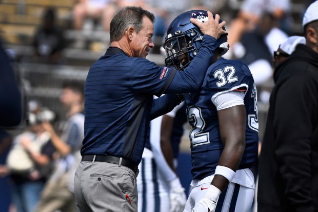 UConn coach Jim Mora, left grabs the helmet of UConn linebacker Oumar Diomande, about to make his first start on defense for the Huskies in Saturdays 59-13 win over CCSU (Jessica Hill/Special to the Courant)