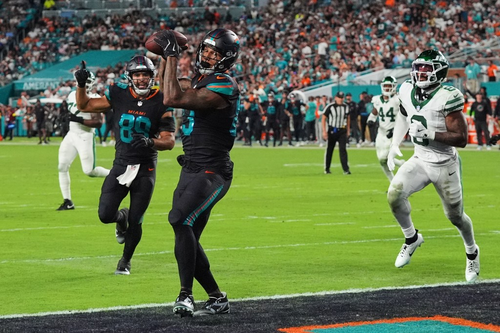 Miami Dolphins tight end Darren Waller catches a touchdown pass as Julian Hill celebrates and New York Jets' Andre Cisco defends.