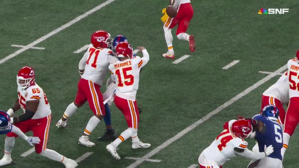 Patrick Mahomes (#15) in white and red uniform throwing a football during a game, surrounded by other players.