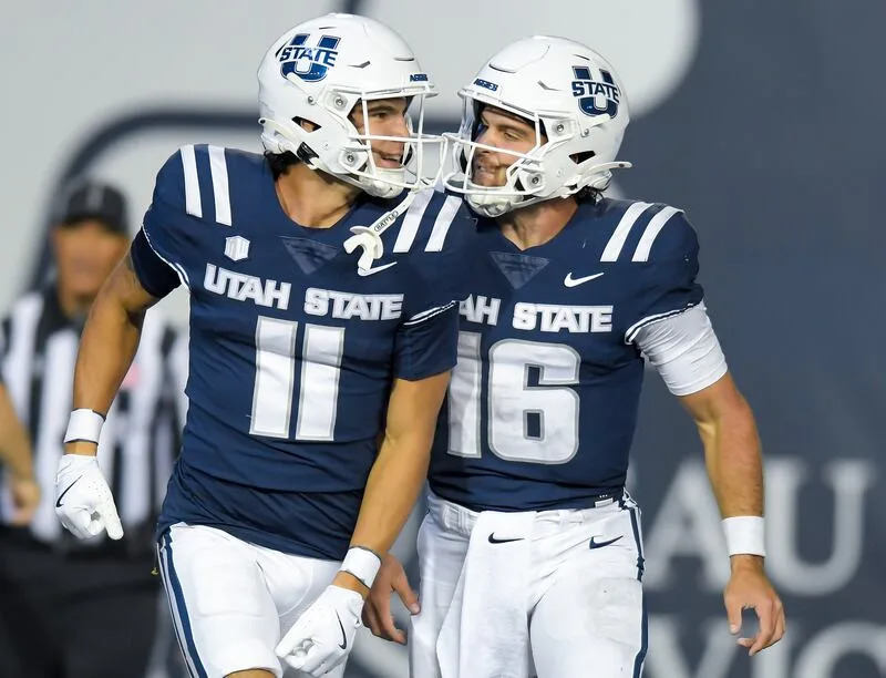 Utah State wide receiver Braden Pegan (11) and quarterback Bryson Barnes (16) celebrate after Pegan scored a touchdown from a Barnes pass against Air Force in the second half Saturday Sept. 13, 2025, in Logan, Utah. | Eli Lucero/Herald Journal