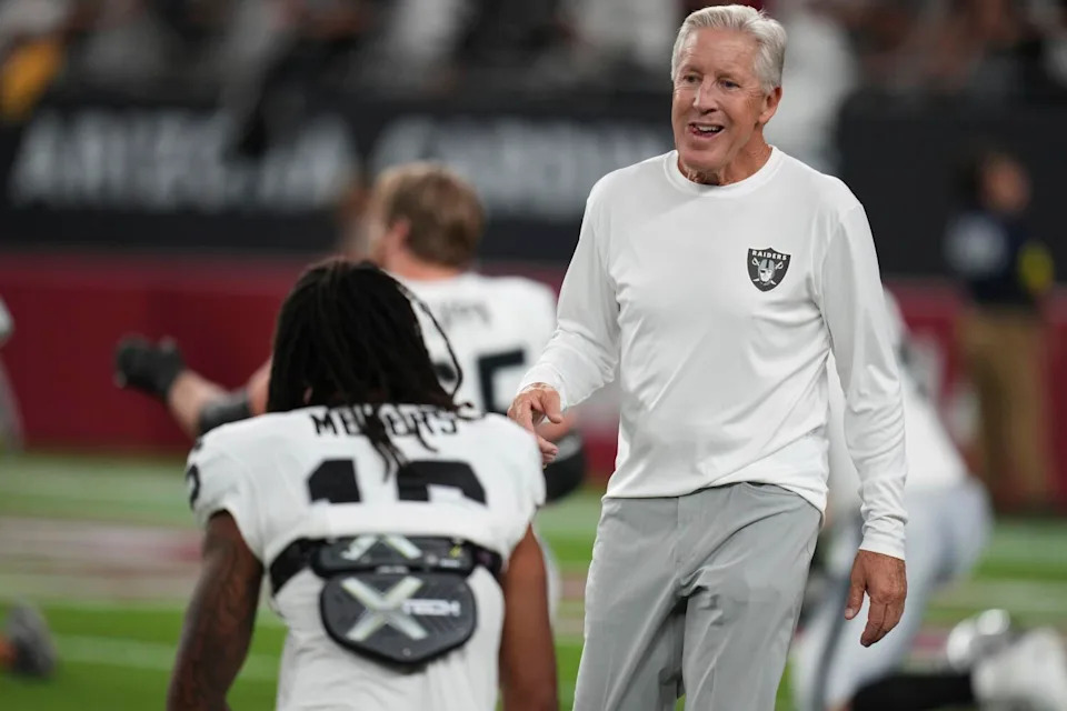 Las Vegas Raiders coach Pete Carroll talks to players as they warm up before a preseason game.