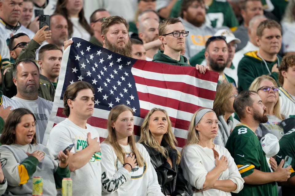 Fans standing for the national anthem at a football game.