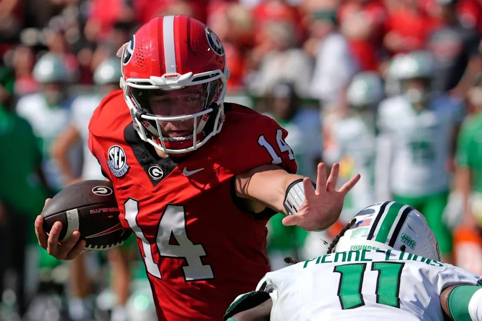 Georgia quarterback Gunner Stockton (14) runs the ball past Marshall defensive back Josh Pierre-Louis (11) during the first half of a NCAA college football game against Marshall in Athens, Ga., on Saturday, August. 30, 2025.