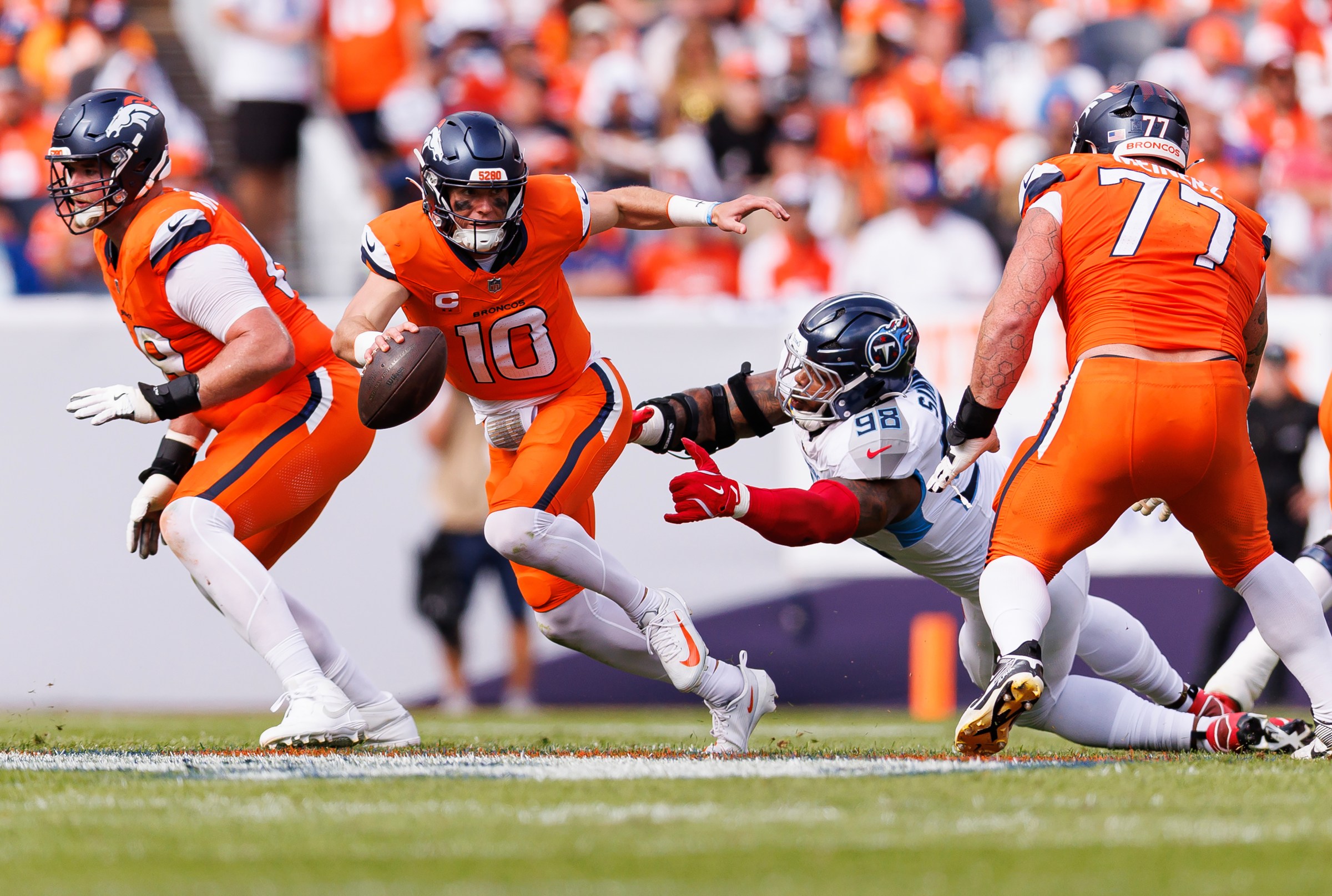 DENVER, COLORADO - SEPTEMBER 07: Bo Nix #10 of the Denver Broncos escapes a tackle by Jeffery Simmons #98 of the Tennessee Titans during an NFL football game, at Empower Field at Mile High on September 7, 2025 in Denver, Colorado. (Photo by Brooke Sutton/Getty Images)