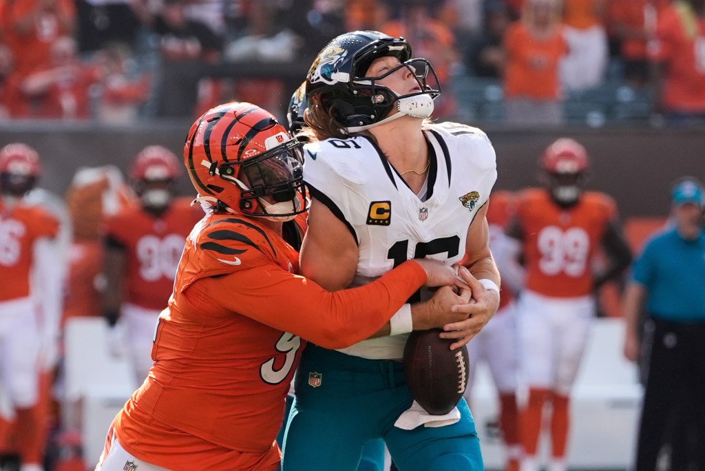 Jacksonville Jaguars quarterback Trevor Lawrence is tackled by a Cincinnati Bengals player.