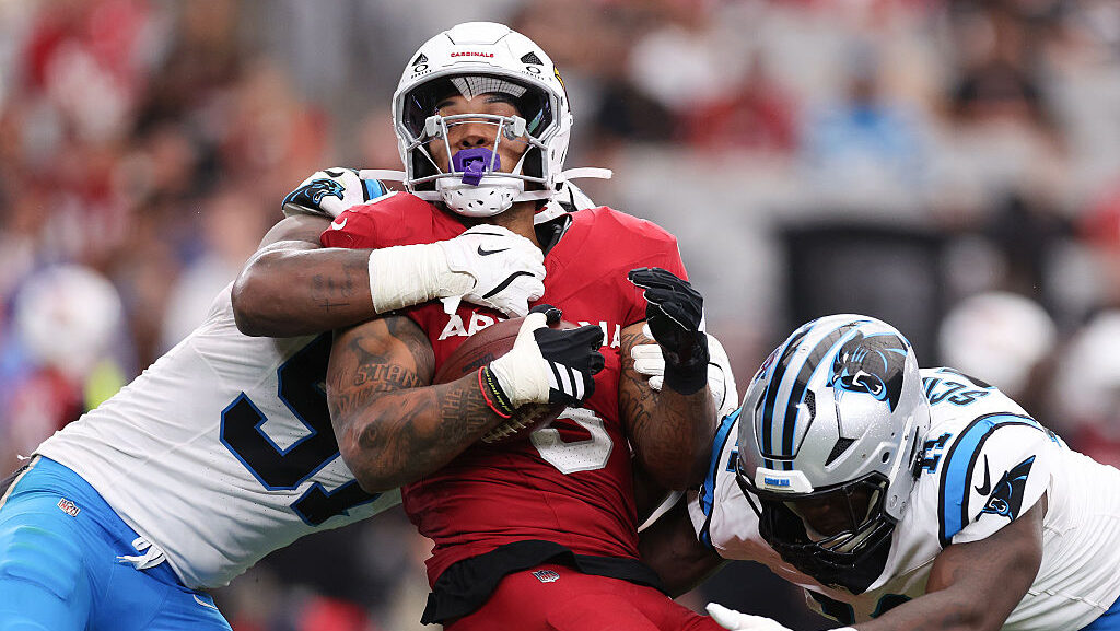 Patrick Jones II #91 and Nic Scourton #11 of the Carolina Panthers tackle James Conner #6 of the Ar...