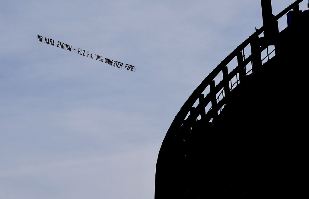 A plane towing a banner reading "MR MARA ENOUGH - PLZ FIX THIS DUMPSTER FIRE" flies over MetLife Stadium before the Giants-Saints game on Dec. 8, 2024.