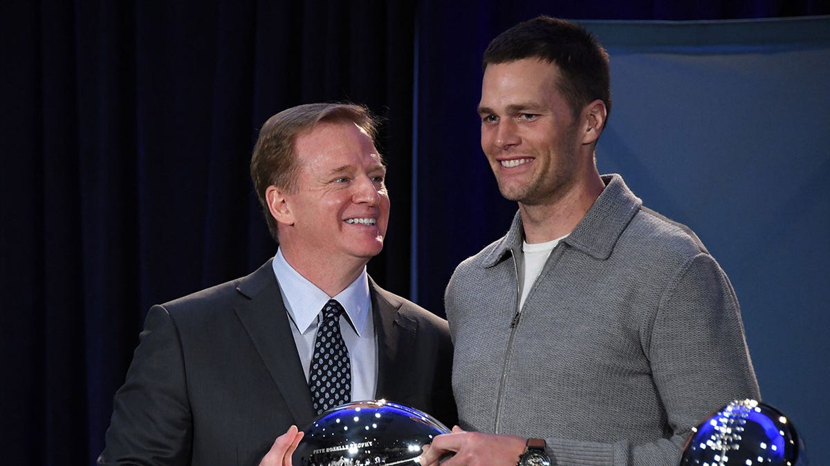 Roger Goodell presents a trophy to Tom Brady