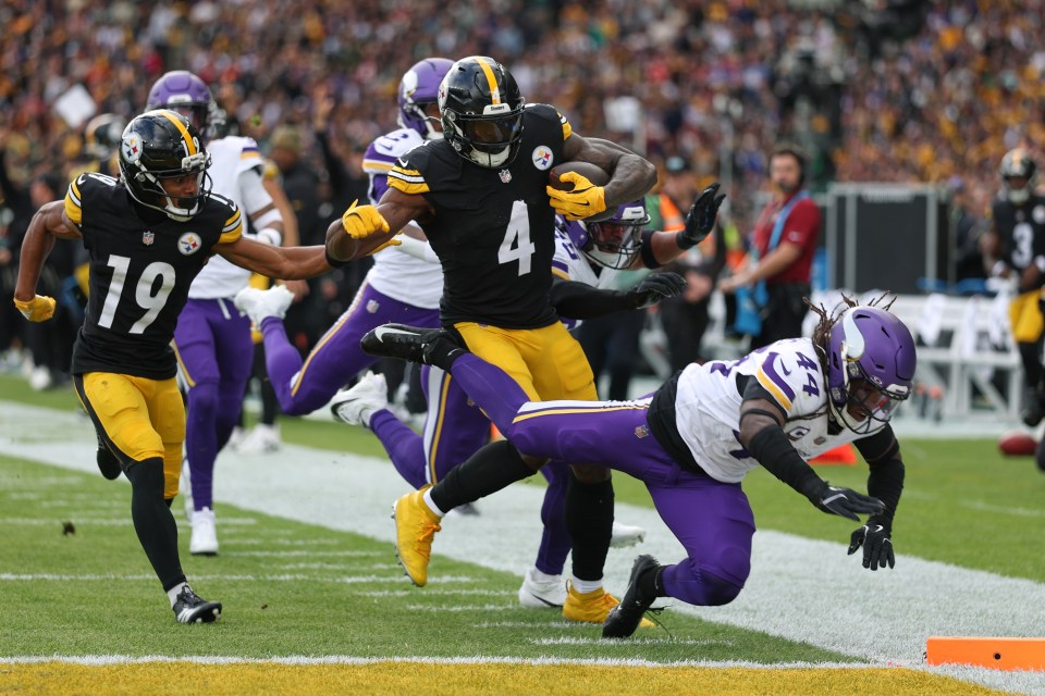 Pittsburgh Steelers player DK Metcalf runs the ball with another Steelers player alongside, while a Minnesota Vikings player falls to the ground.
