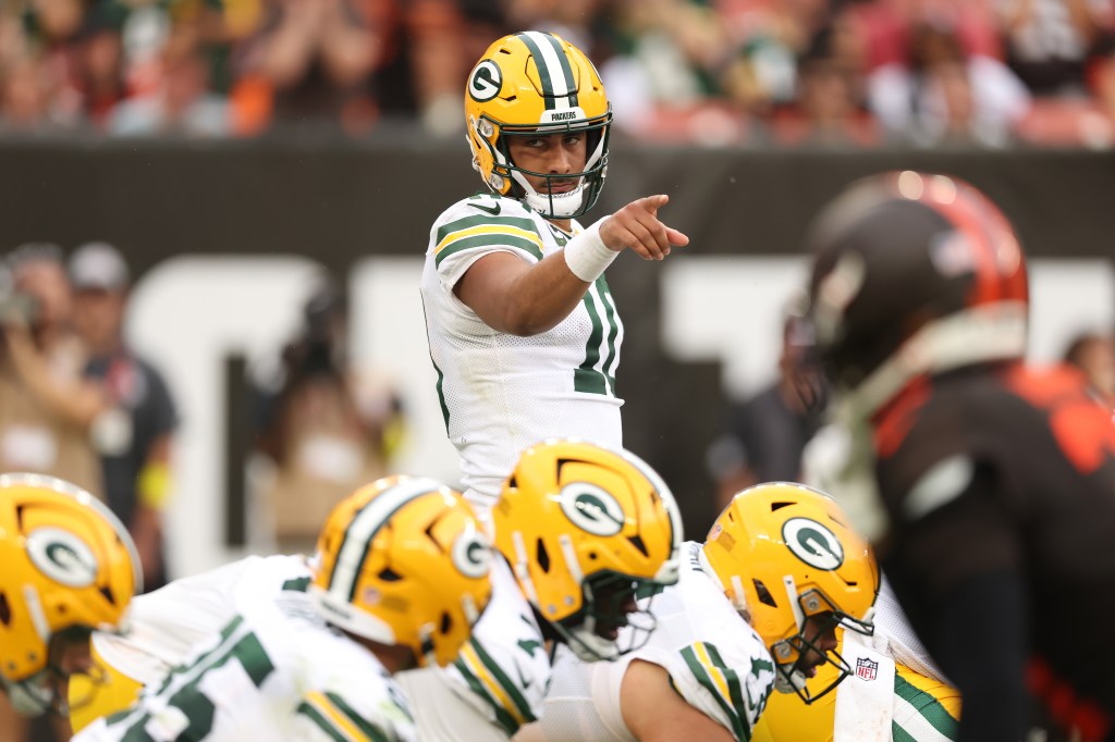 Green Bay Packers quarterback Jordan Love points to a player while standing on the field.