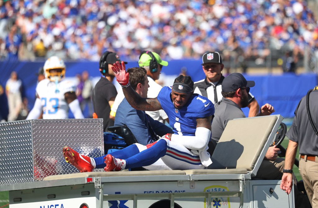New York Giants wide receiver Malik Nabers waving to fans as he is carted off the field due to injury.