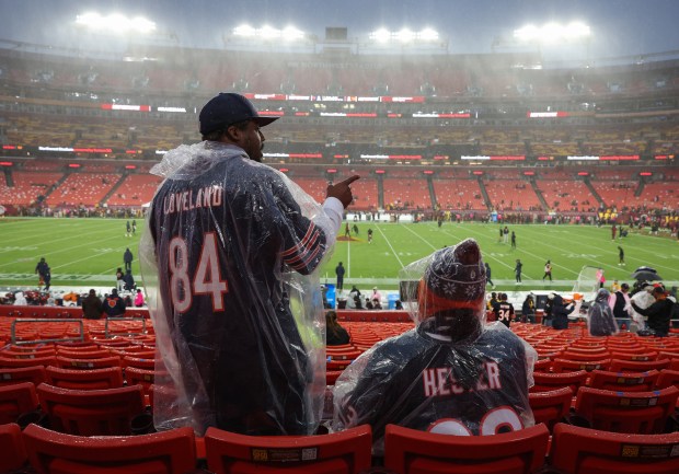 Two fans reach their seats in a steady drizzle before...