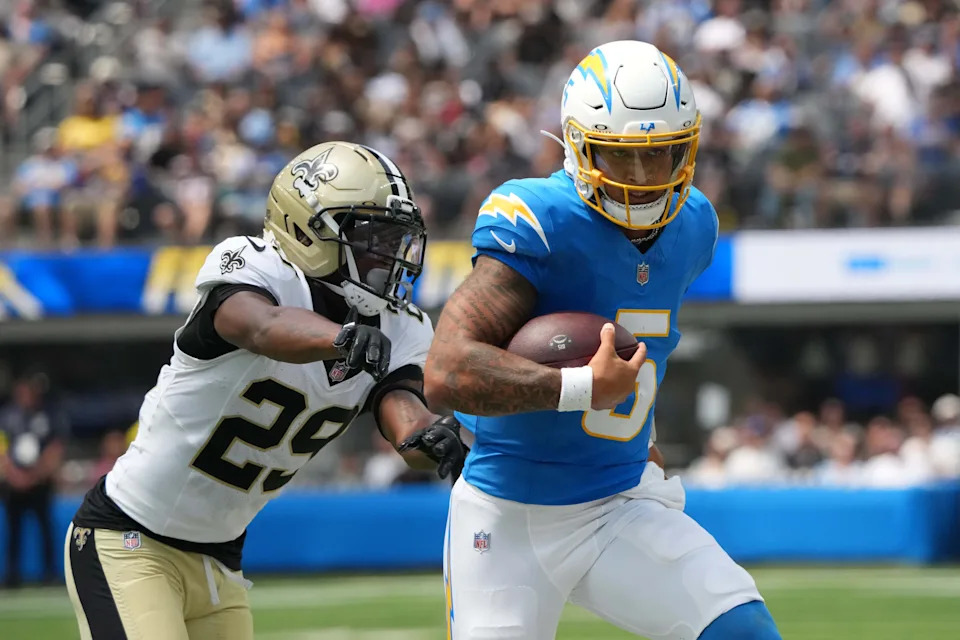 Aug 10, 2025; Inglewood, California, USA; Los Angeles Chargers quarterback Trey Lance (5) carries the ball against New Orleans Saints cornerback Quincy Riley (29) in the first half at SoFi Stadium. Mandatory Credit: Kirby Lee-Imagn Images