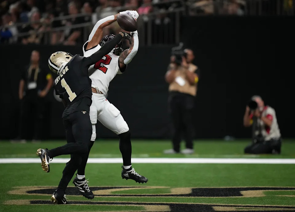 Tampa Bay Buccaneers wide receiver Emeka Egbuka catches a pass under pressure from New Orleans Saints cornerback Alontae Taylor.