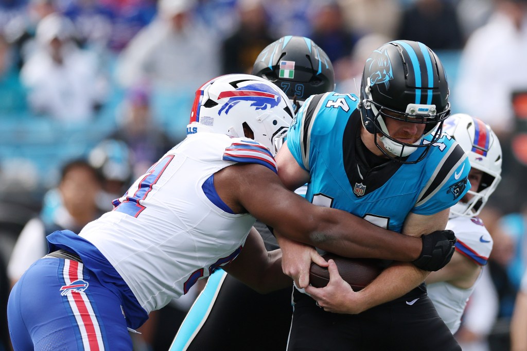A Buffalo Bills player in white and blue jersey tackling a Carolina Panthers player in blue and black jersey during a game.