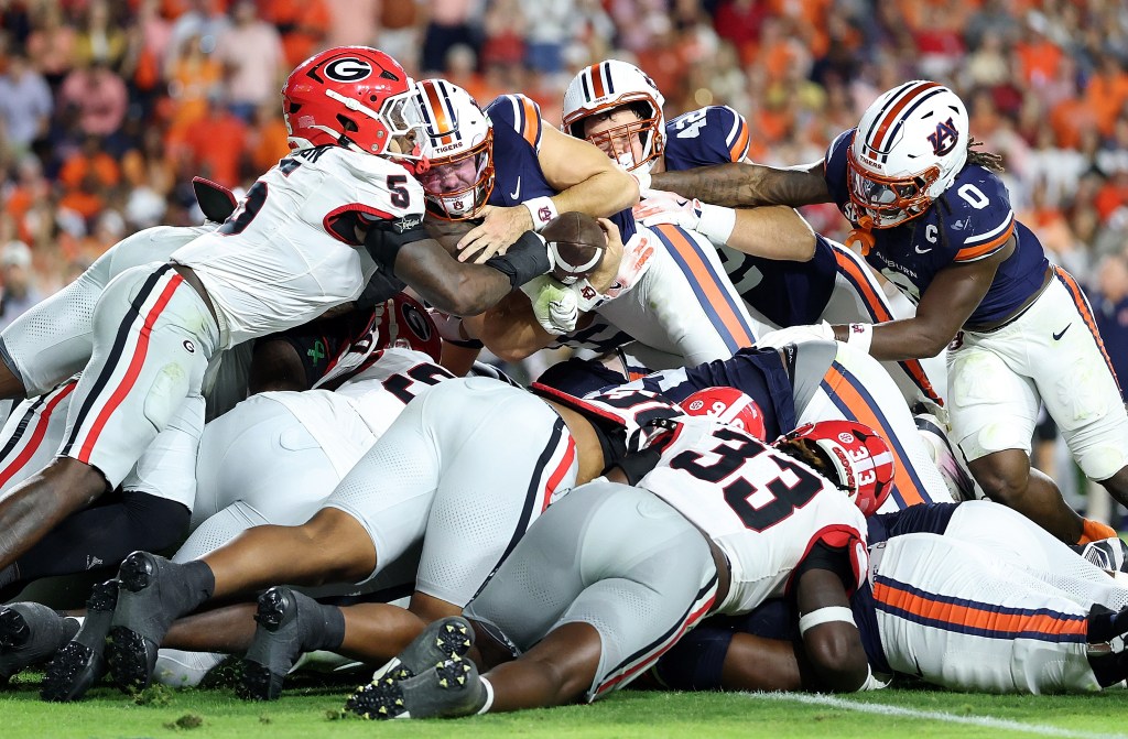 Georgia Bulldogs players tackling an Auburn Tigers player who is diving for the end zone.