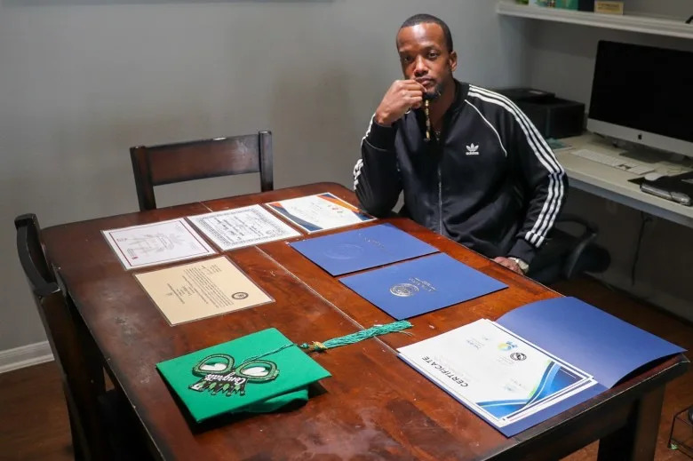 After prison, Leon Dillard went through a city-led reentry program, where he first found out about the solar installation opportunity. On his table are laminated copies of his new diplomas and certificates. (Adam Mahoney/Capital B)