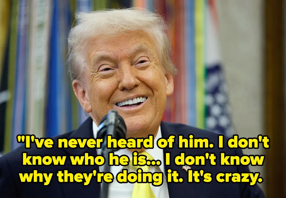 Man in a suit with a bright tie smiling behind a microphone, with colorful flag-like elements in the background