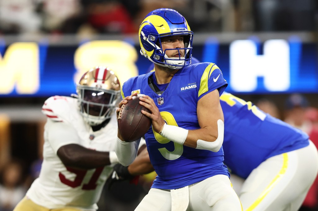 Matthew Stafford preparing to throw the football as Sam Okuayinonu approaches from behind.