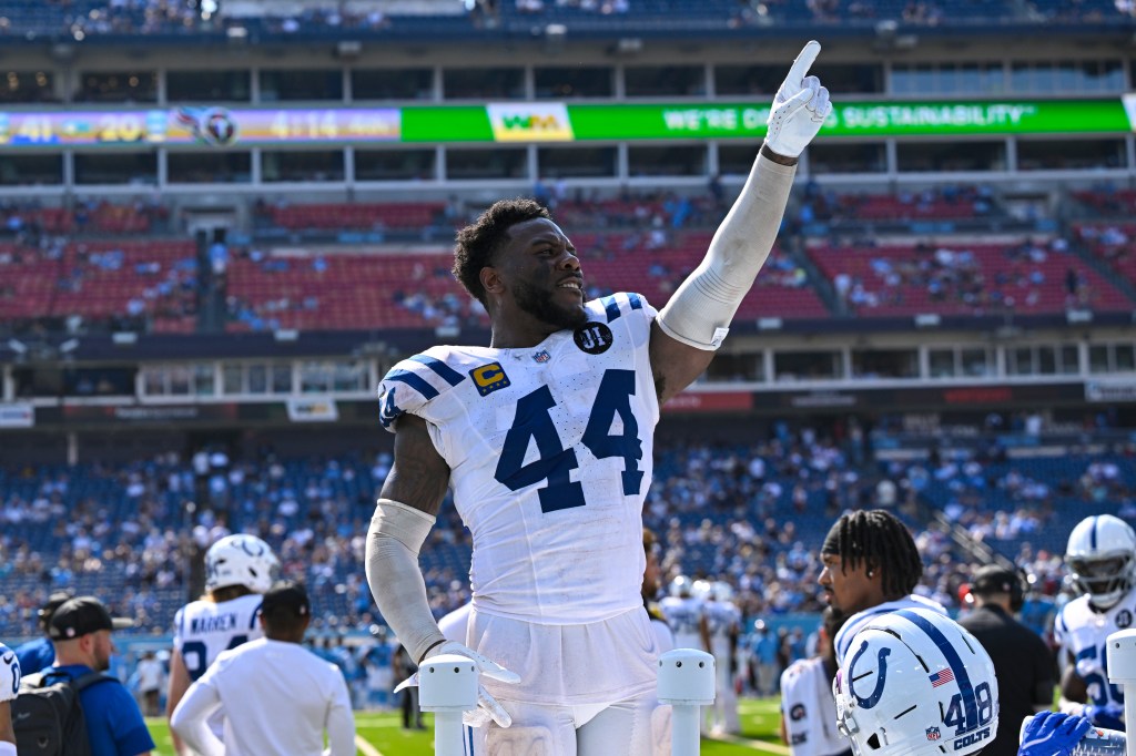 Indianapolis Colts linebacker Zaire Franklin points his finger up while standing on the sideline of a football field.