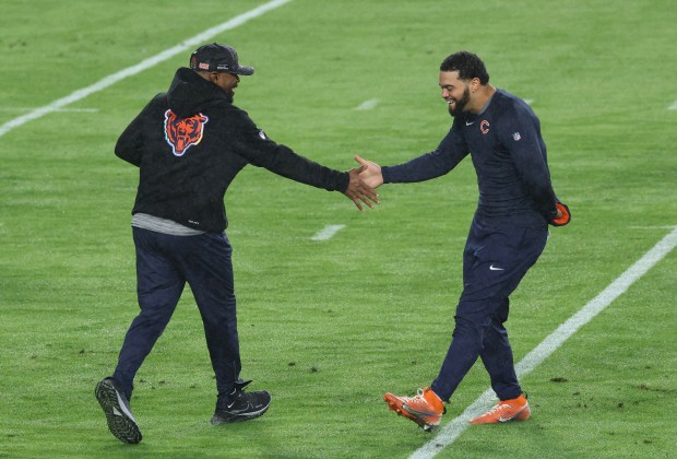 Bears quarterback Caleb Williams, right, greets a member of the coaching staff on the field before a game against the Commanders at Northwest Stadium Oct. 13, 2025, in Landover, Maryland. (John J. Kim/Chicago Tribune)