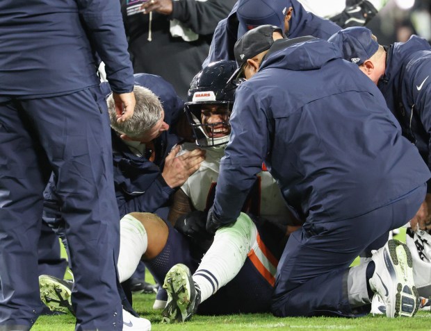 Bears linebacker Noah Sewell grimaces in pain while being attended...