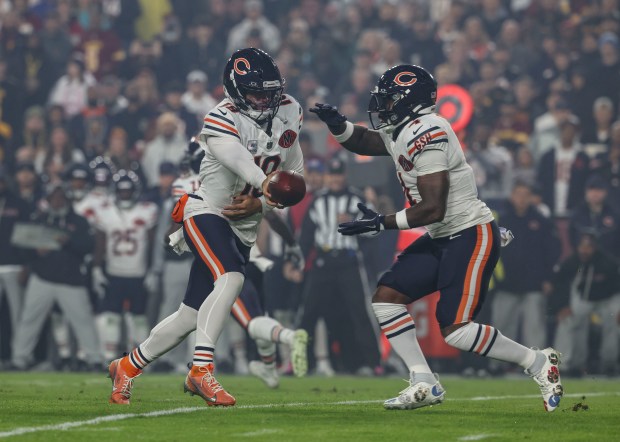 Chicago Bears quarterback Caleb Williams hands off to running back...
