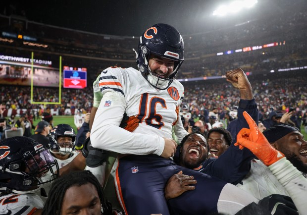 Bears kicker Jake Moody is lifted by his teammates as...