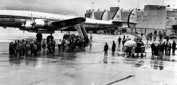 Enthusiasm runs high among the crowd that braved the rain to watch the first planes take off as O'Hare International Airport, which was the world's biggest at the time, was opened to civilian use on Oct. 29, 1955. Air France liner in photo was one of first to inaugurate airport. (Chicago American photo)