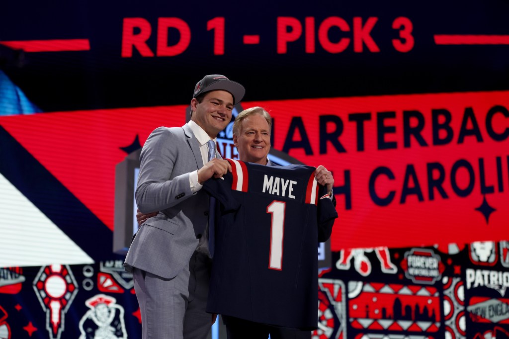 Drake Maye (left) and Roger Goodell (right) holding up a New England Patriots jersey with Maye's name and number 1 on it at the NFL Draft.