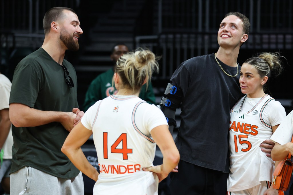 Haley Cavinder #14 and Hanna Cavinder #15 of the Miami Hurricanes meet with Jake Ferguson of the Dallas Cowboy and Carson Beck of the Miami Hurricanes after defeating the Virginia Cavaliers 77-74 at Watsco Center on January 30, 2025 in Coral Gables, Florida. 