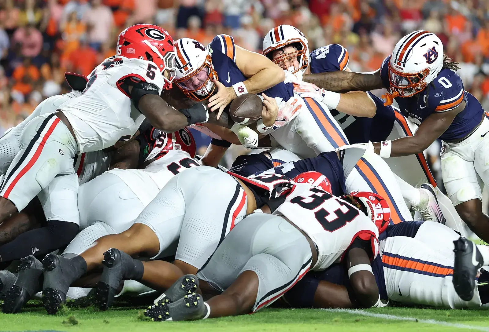 Raylen Wilson #5 of the Georgia Bulldogs punches out the ball as Jackson Arnold #11 of the Auburn Tigers