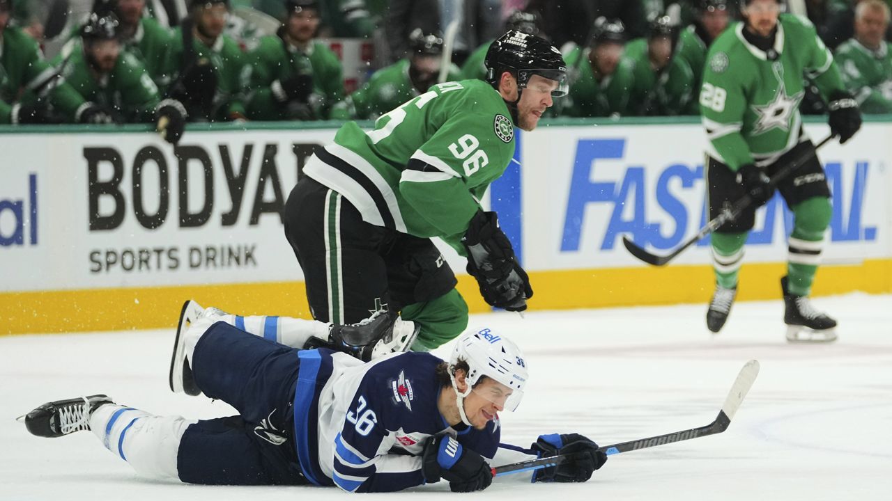 Winnipeg Jets center Morgan Barron (36) falls to the ice competing against Dallas Stars' Mikko Rantanen (96) in the first period of Game 3 of a second-round NHL hockey playoff series in Dallas, Sunday, May 11, 2025. (AP Photo/Julio Cortez)