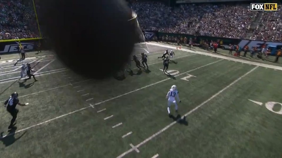 An American football being kicked during a game as a Fox NFL camera captures the event.