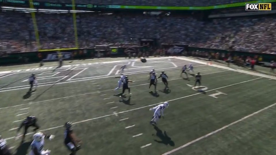 A football game in progress with players on the field and a ball in mid-air.