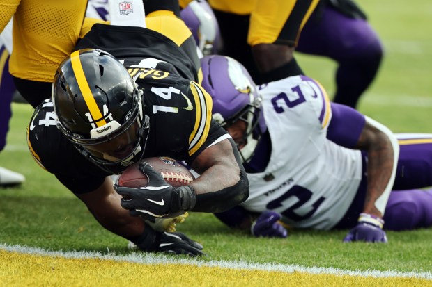 Pittsburgh Steelers running back Kenneth Gainwell (14) scores a touchdown as he flips over Minnesota Vikings cornerback Isaiah Rodgers (2) during an NFL football game at Croke Park in Dublin, Sunday, Sept. 28, 2025. (Gregory Payan/AP Content Services for the NFL)