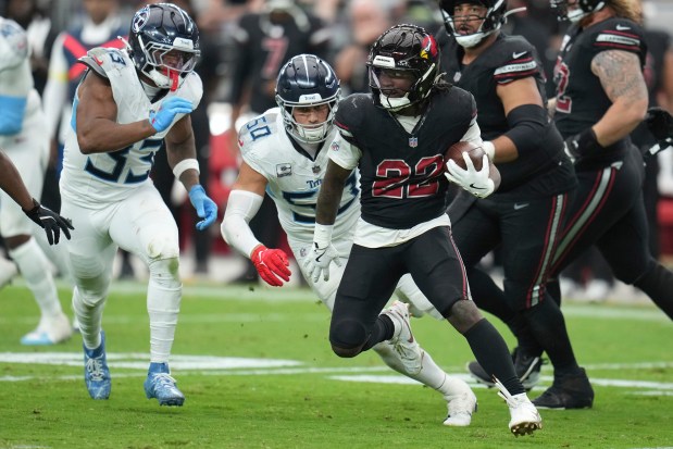 Arizona Cardinals running back Michael Carter (22) runs the ball against the Tennessee Titans linebacker Cedric Gray (33) and linebacker Cody Barton (50) during the second half of an NFL football game Sunday, Oct. 5, 2025, in Glendale, Ariz. (AP Photo/Rick Scuteri)