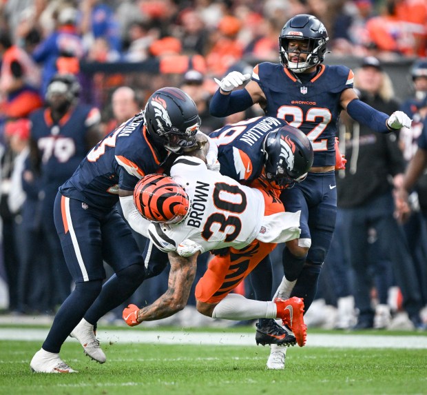 Jahdae Barron (23) and Ja'Quan McMillian (29) of the Denver Broncos tackle Chase Brown (30) of the Cincinnati Bengals as Brandon Jones (22) priovides support during the first quarter at Empower Field at Mile High on Monday, Sept. 29, 2025. (Photo by AAron Ontiveroz/The Denver Post)