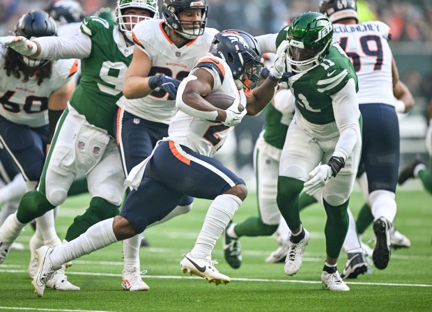 J.K. Dobbins (27) of the Denver Broncos stiff arms Jermaine Johnson II (11) of the New York Jets during the first quarter at Tottenham Hotspur Stadium in London on Sunday, Oct. 12, 2025. (Photo by AAron Ontiveroz/The Denver Post)