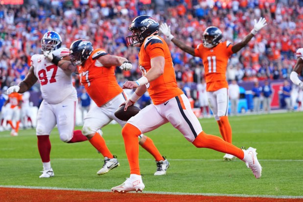 Denver Broncos quarterback Bo Nix, middle, scores against the New York Giants during the second half of an NFL football game in Denver, Sunday, Oct. 19, 2025. (AP Photo/Jack Dempsey)