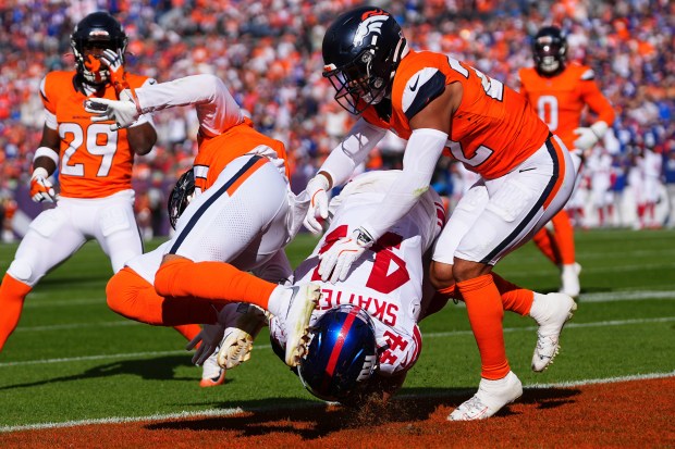 New York Giants running back Cam Skattebo, bottom, scores past...