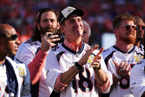 Former Denver Broncos quarterback Peyton Manning, middle, applauds with teammates...