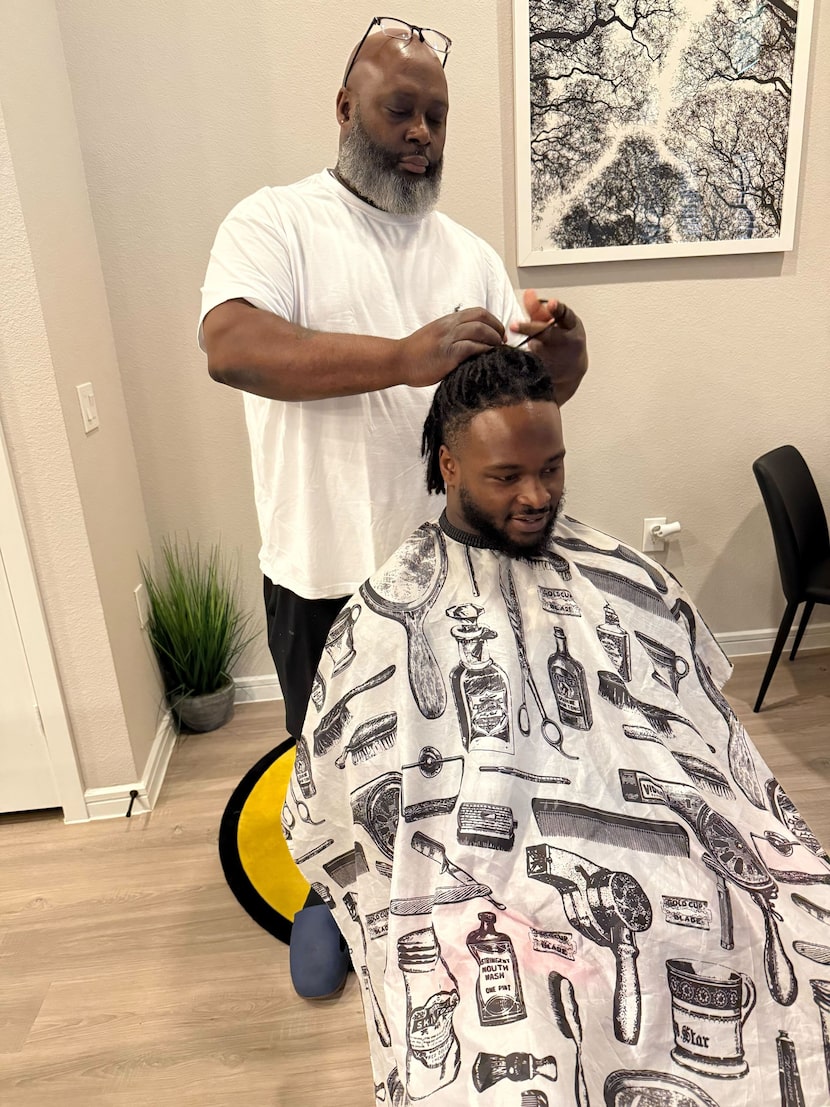 Cowboys running back Javonte Williams sits for his weekly haircut from his father, Jermaine,...