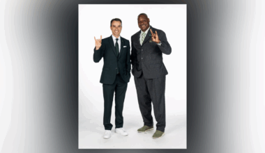 Rob Higgins and Derrick Brooks pose together, both wearing suits and making the USF Bulls hand sign to celebrate Brooks’ new role as chief operating officer of USF Athletics.