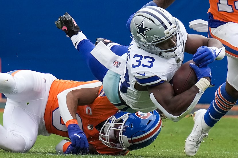 Dallas Cowboys running back Javonte Williams (33) is brought down by Denver Broncos safety...