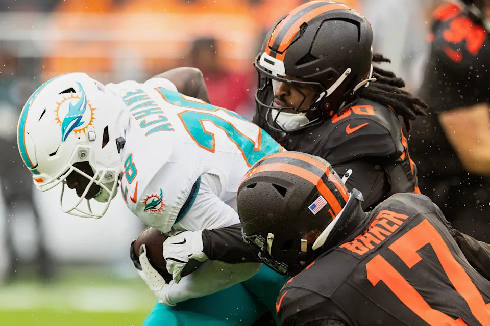 Oct 19, 2025; Cleveland, Ohio, USA; Cleveland Browns linebackers Devin Bush (30) and Jerome Baker (17) tackle Miami Dolphins running back De'Von Achane (28) during the first quarter at Huntington Bank Field. Mandatory Credit: Scott Galvin-Imagn Images