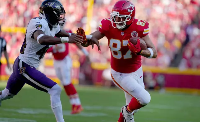 Kansas City Chiefs tight end Travis Kelce (87) runs with the ball as Baltimore Ravens cornerback Marlon Humphrey (44) defends during the first half of an NFL football game Sunday, Sept. 28, 2025, in Kansas City, Mo. (AP Photo/Ed Zurga)