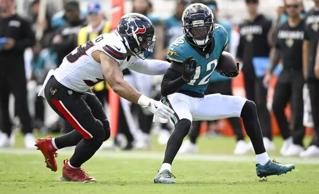 Jacksonville Jaguars wide receiver Travis Hunter, right, tries to avoid a tackle by Houston Texans linebacker Henry To'Oto'O after making a catch during the second half of an NFL football game Sunday, Sept. 21, 2025, in Jacksonville, Fla. (AP Photo/Phelan M. Ebenhack)