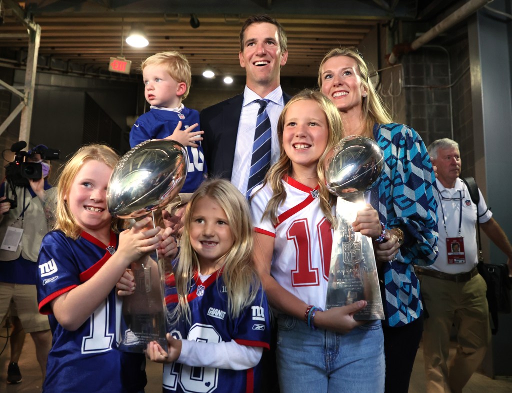 Eli Manning of the New York Giants with his family and the two Super Bowl trophies after his ring of honor induction ceremony during halftime of the game between the New York Giants and the Atlanta Falcons at MetLife Stadium on September 26, 2021.