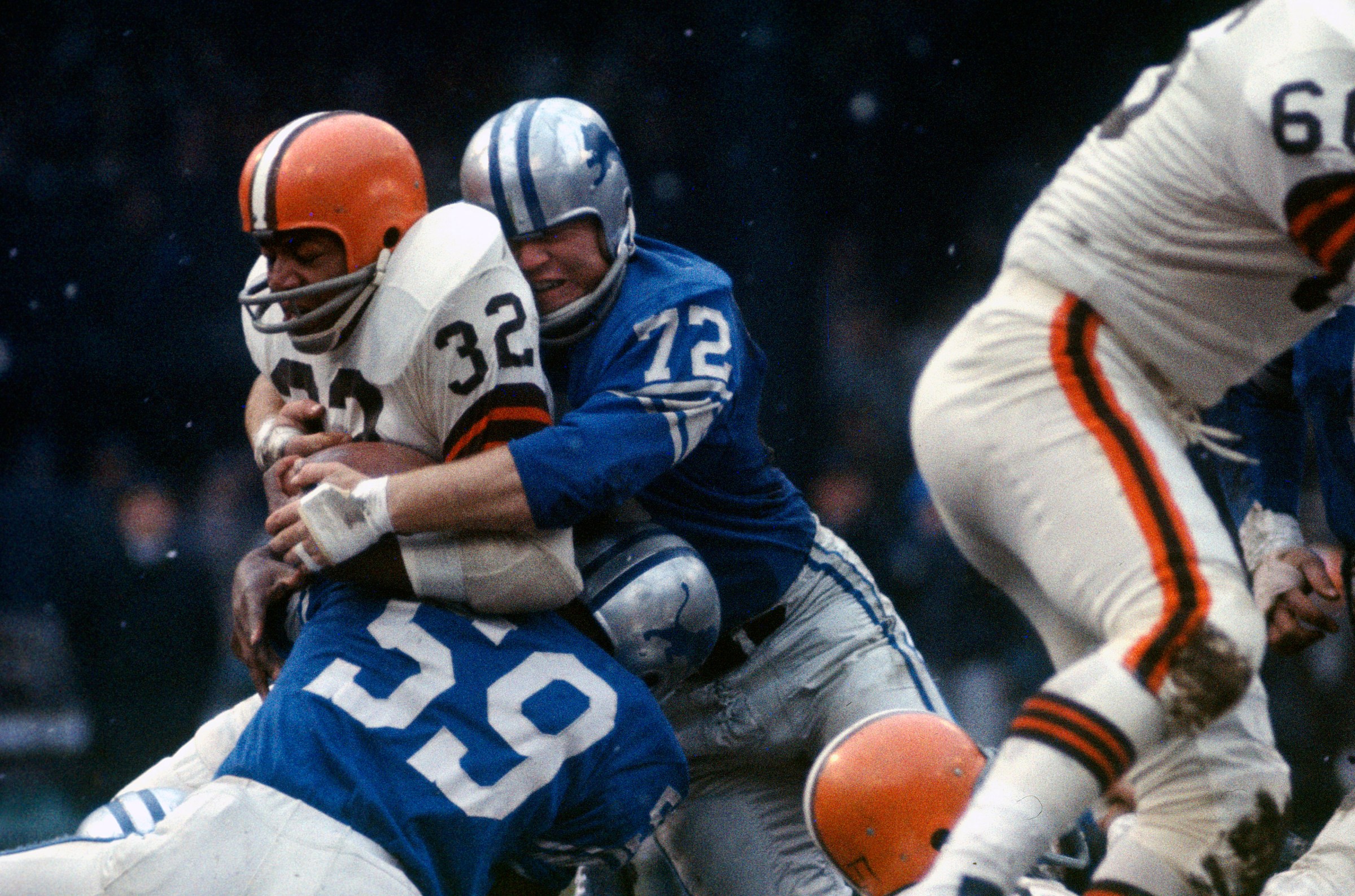 DETROIT, MI - DECEMBER 8: Jim Brown #32 of the Cleveland Browns gets tackled by Ernie Clark #59 and Floyd Peters #72 of the Detroit Lions during an NFL football game December 8, 1963 at Tiger Stadium in Detroit, Michigan. Brown played for the Browns from 1957-1965. (Photo by Focus on Sport/Getty Images)
